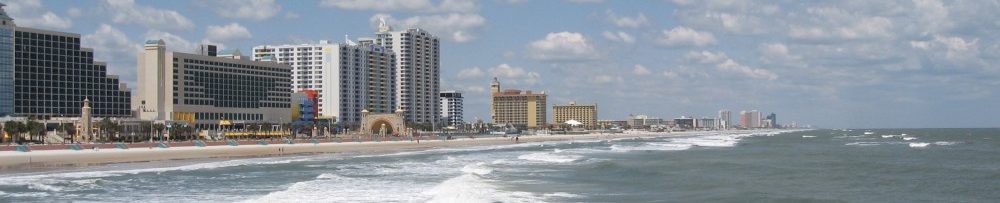 A view of the Daytona Beach Boardwalk, Coquina Clock Tower, Ocean Walk Shops, Bandshell, and several hotels from the Daytona Beach Pier.